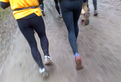 Dreckbespritzte Läufer-Beine beim 26-km-Lauf