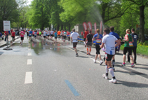 Ein Wasserstrahl bringt Erfrischung für die Marathon-Läufer