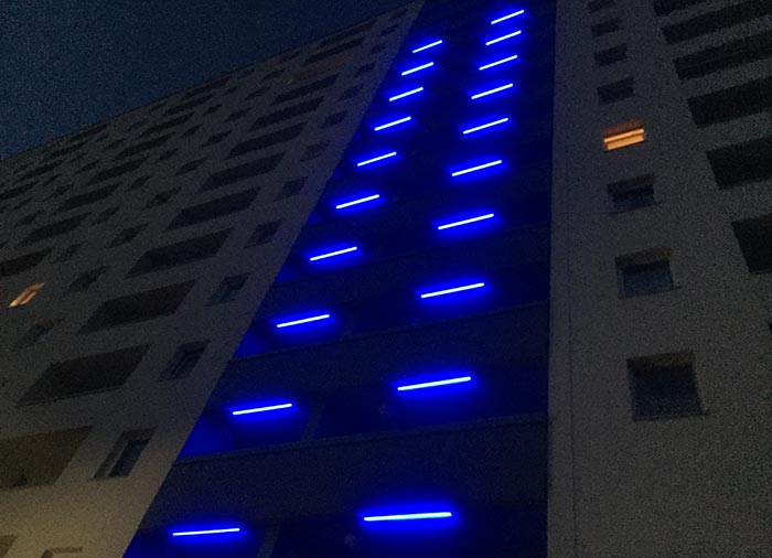 Reihe von blauen Lichtbalken an einem Hochhaus