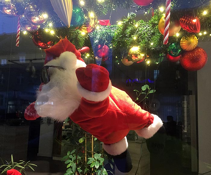 Fliegende Weihnachtsmannfigur mit Sonnenbrille im Schaufenster