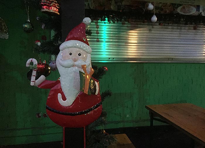 Weihnachtsmann-Figur vor einem grün gestrichenen Pizza-Kiosk