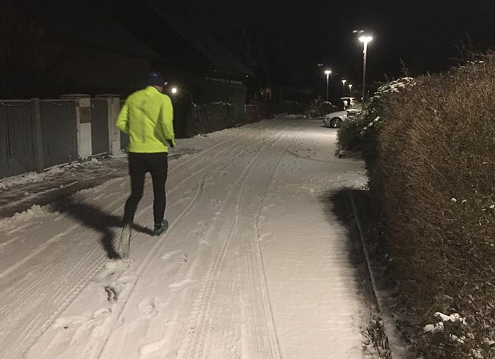 Läufer auf morgendunkler verschneiter Straße