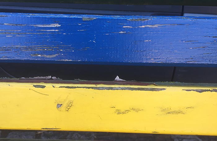 Holzlatten einer Parkbank in blau und gelb