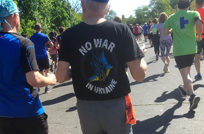 Läufer mit Laufshirt „No War in Ukraine“ und gelb-blauer Friedenstaube