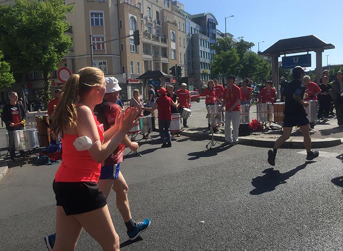 Eine Trommelgruppe in roten Shirts treibt die Läuferinnen und Läufer auf dem 1. Kilometer an