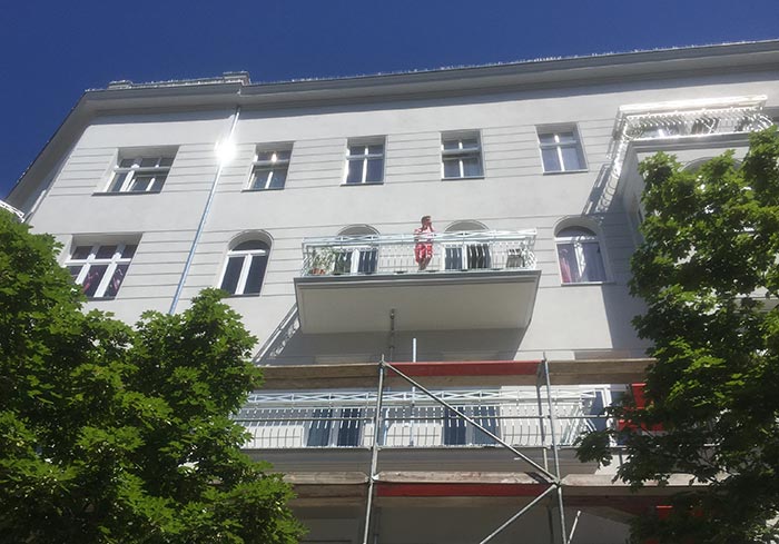 Zuschauerin auf dem Balkon eines weißen Hauses in der Kantstraße