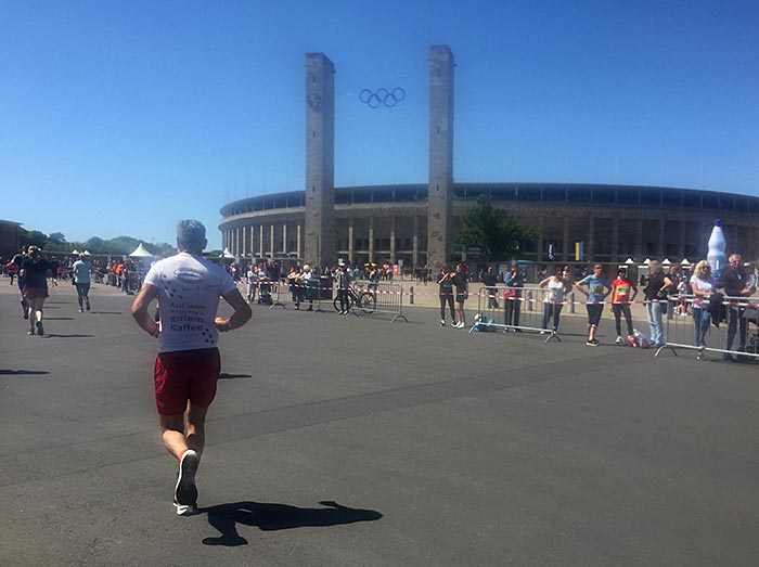 Olympiastadion mit den Olympischen Ringen, davor vereinzelte Läufer