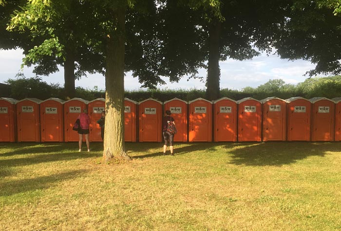 Orange WC-Häuschen in einer breiten Reihe