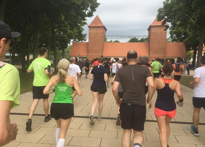 Läuferinnen und Läufer laufen auf das historische Eingangstor zu