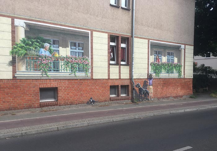Wandbild auf dem täuschend echt Balkone mit Menschen aufgemalt sind