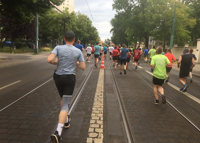 Läufer auf einer breiten Straße mit Gleisen der Tram