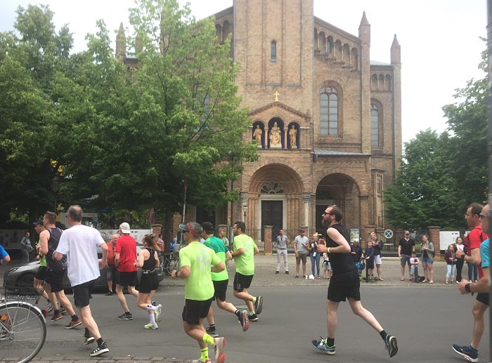 Läufer biegen vor Kirche um die Kurve