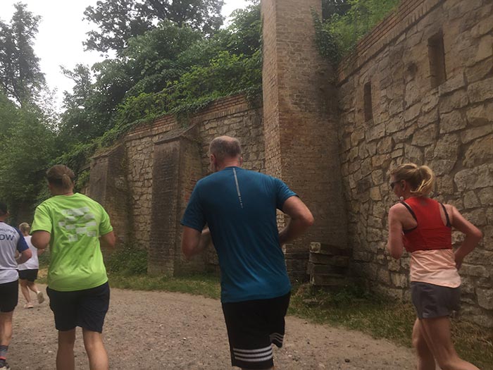 Läuferinnen und Läufer laufen an alter Mauer entlang