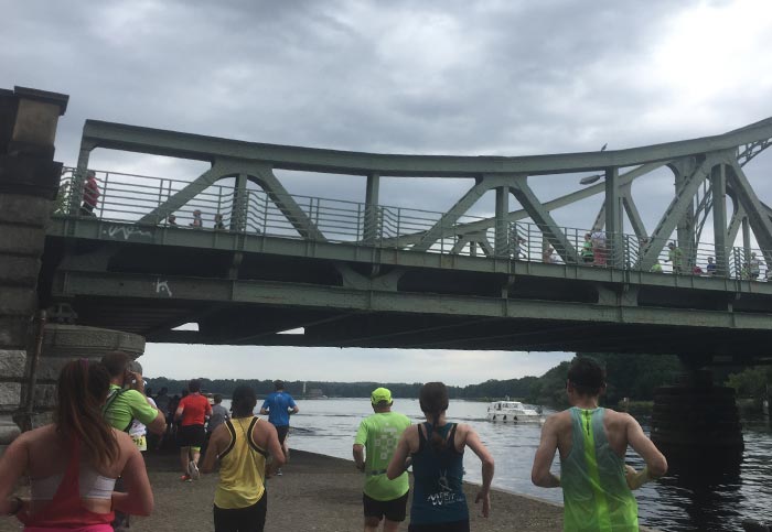 Läuferinnen und Läufer unterhalb der Glienicker Brücke, auf der oben die Nachfolgenden laufen