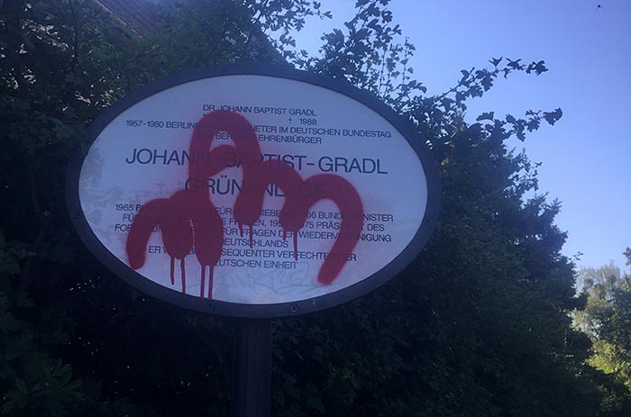 Schild mit graffiti-verschmierter Erläuterung zu Johann Baptist Gradl