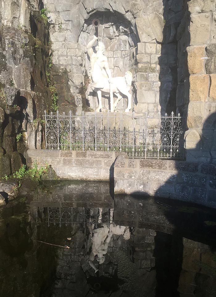 Weiße Statue eines Kentauren spiegelt sich im Wasserbecken