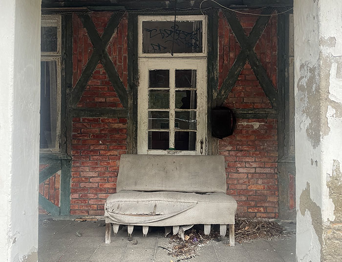 Altes Holzfenster des verlassenen Bahnhofs, darunter ein altes Sofa