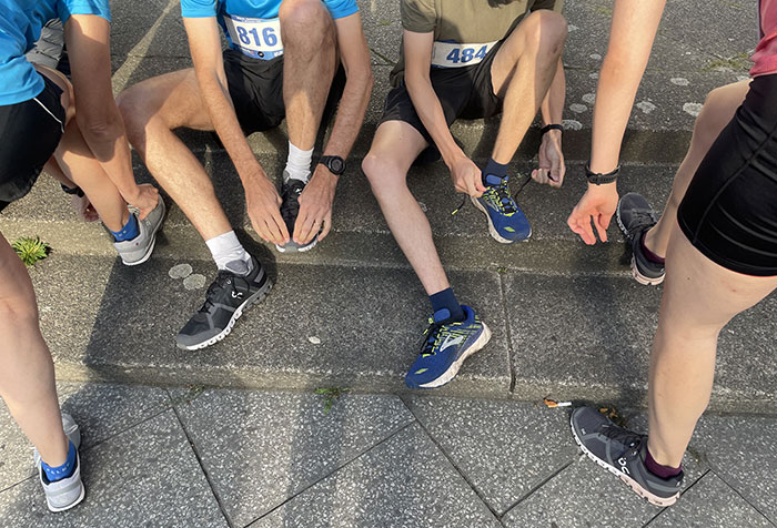 Blick auf die Beine von 4 Läuferinnen und Läufern, die sich gerade die Laufschuhe zubinden