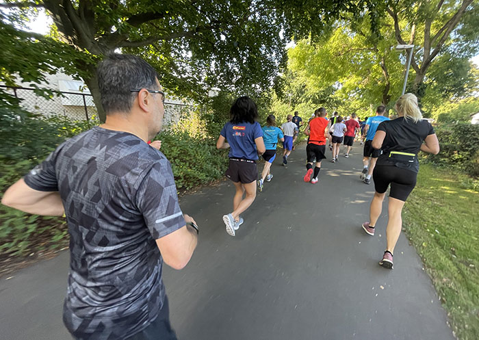 Läuferinnen und Läufer auf dem Weg neben einer Kleingartenanlage