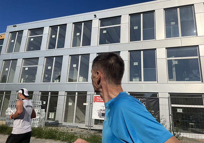 Läufer vor einem Schulneubau, noch mit Hersteller-Aufklebern an den großen Fenstern