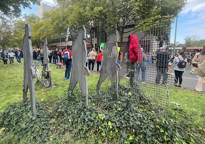 Metall-Skulptur mit 5 Menschenfiguren, im Hintergrund die Marathon-Zuschauer:innen