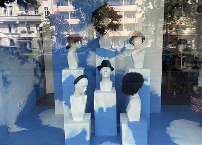 Schaufenster-Dekoration mit weißen Köpfen, die unterschiedlichen Kopfschmuck tragen