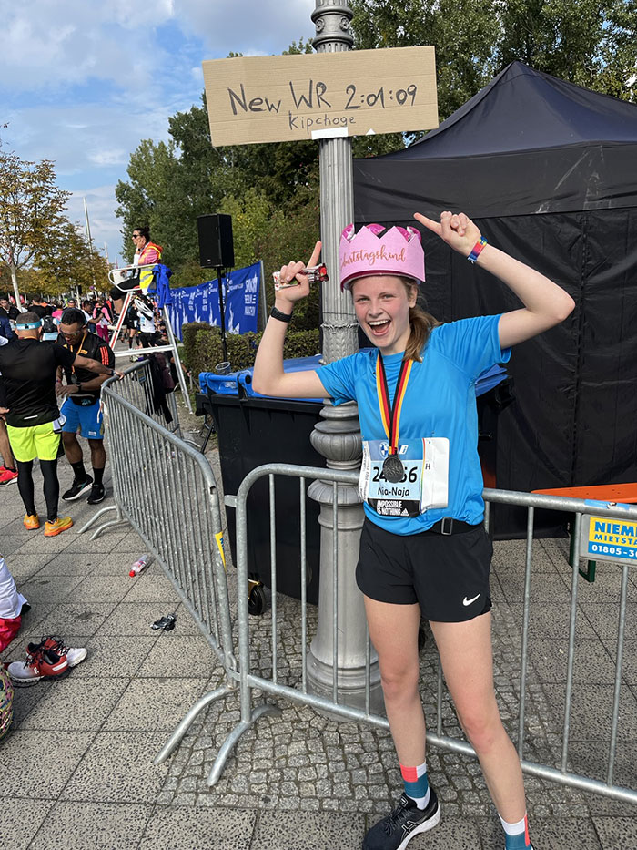 Jubelnde junge Marathon-Läuferin mit Medaille um den Hals