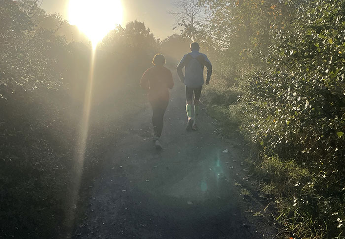 Läuferin und Läufer im Gegenlicht der aufgehenden Sonne