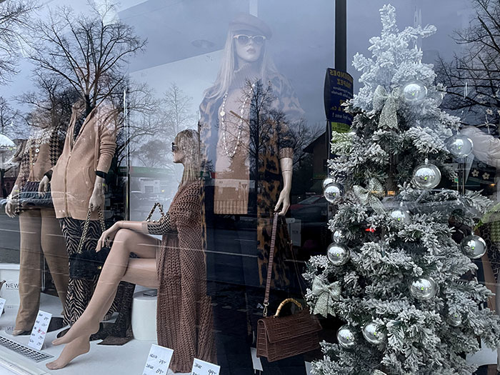 Schaufenster eines Modegeschäfts mit weißem Weihnachtsbaum und Schaufensterpuppen