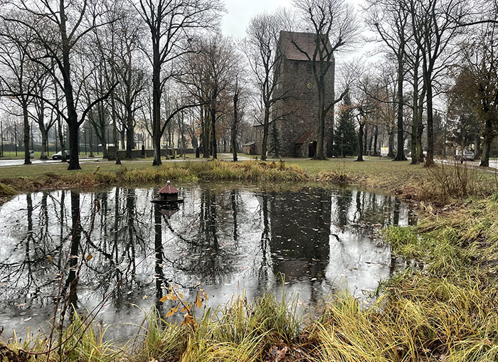 Blick über den kleinen Dorfteich auf die Dorfkirche Marienfelde, die sich mit den umgebenden Bäumen im Teich spiegelt