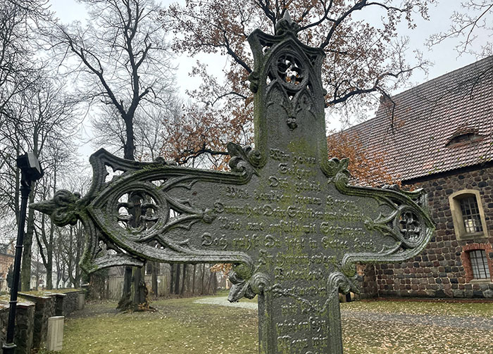 Kunstvoll verziertes altes Metall-Grabkreuz auf dem Kirchhof