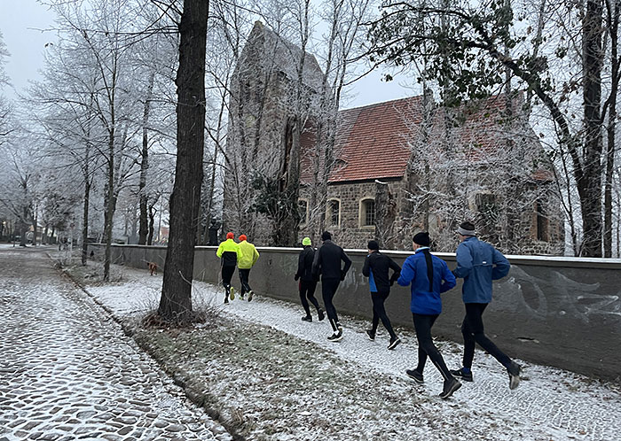 Läufergruppe läuft an der alten Marienfelder Dorfkirche vorbei