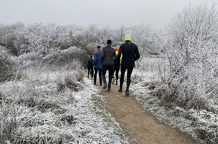 Laufgruppe läuft im winterlichen Freizeitpark Marienfelde einen Hang hinab