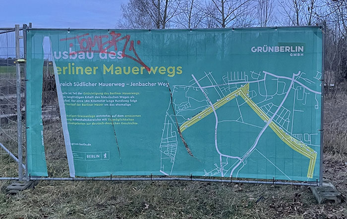 Banner an Bauzaun: Ausbau des Berliner Mauerwegs