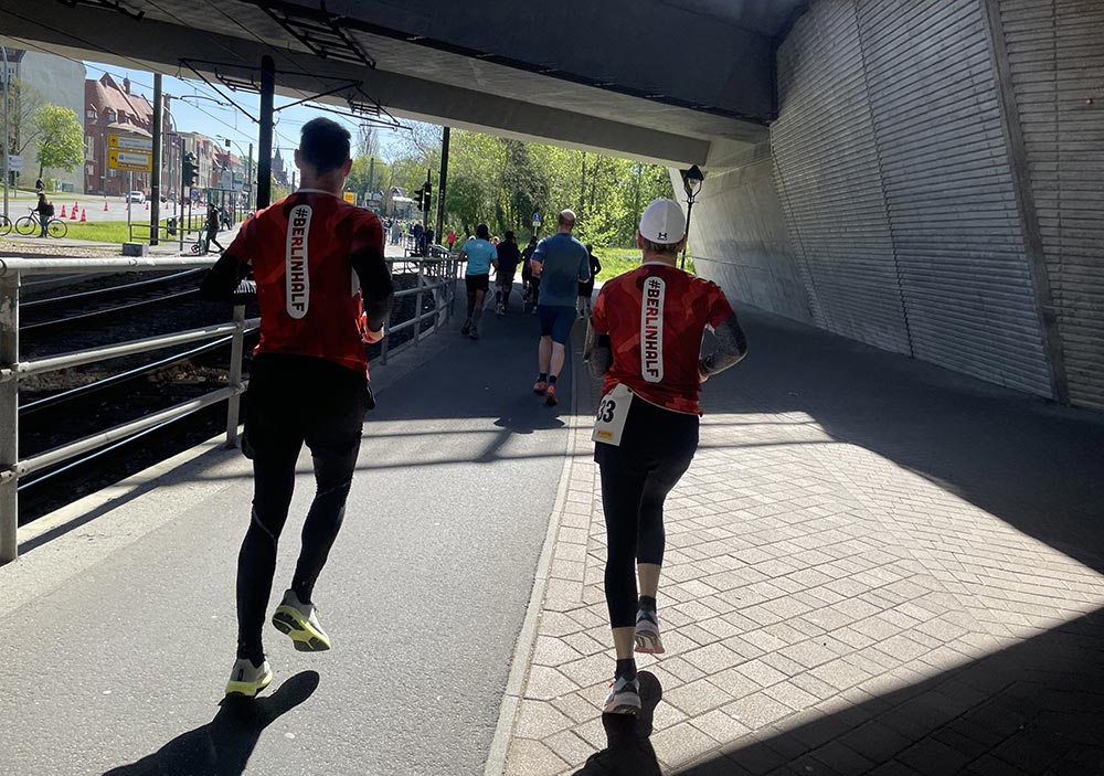 Laufpaar mit roten Shirts unter einer Brücke