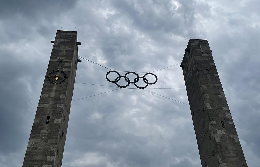 Die Olympischen Ringe zwischen den beiden Türmen am Berliner Olympiastadion gegen einen dunkel wolkigen Himmel