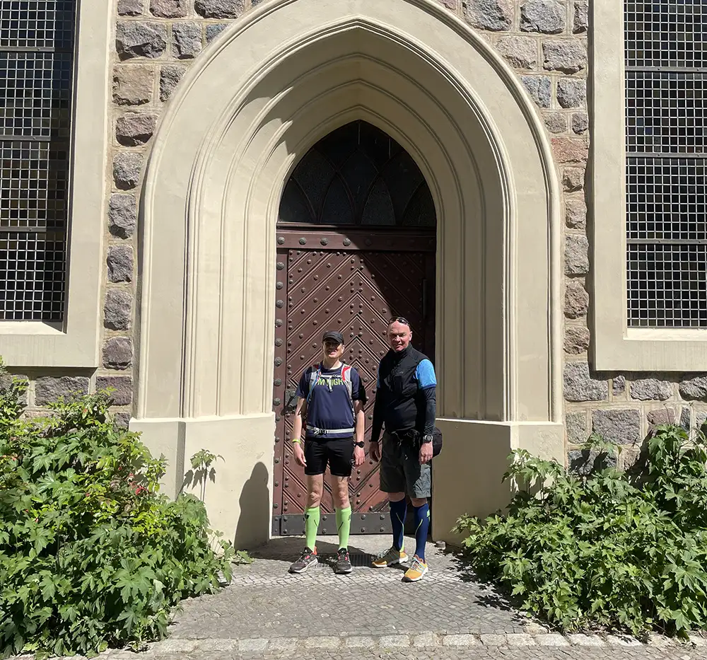 Läufer und Radfahrer posieren vor einem Tor der Kirche