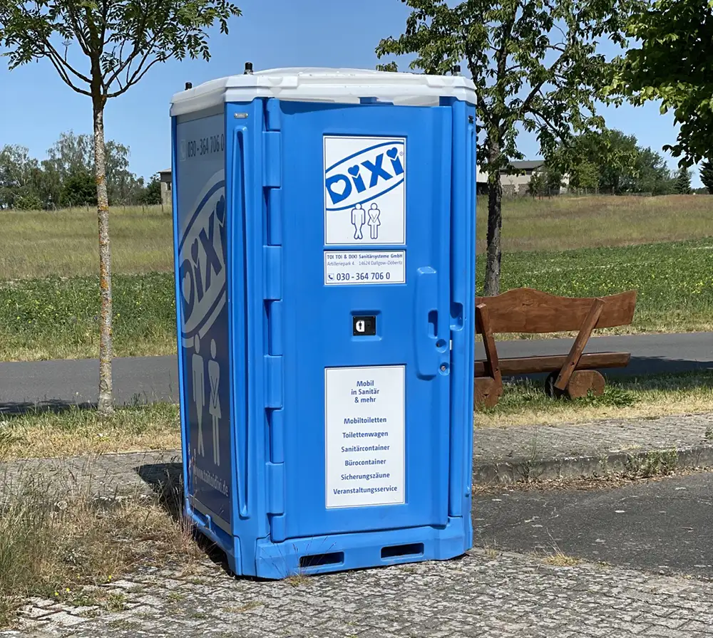Blaue Dixi-Toilette am Straßenrand