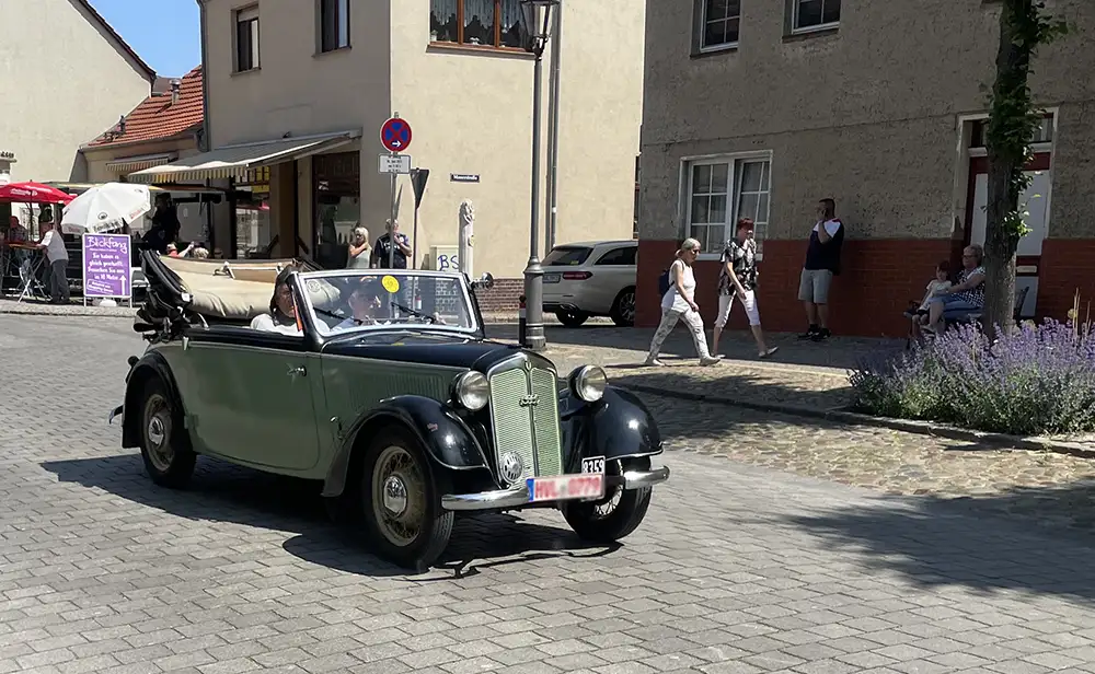 Lindgrün-schwarzer Oldtimer fährt auf der Straße vorbei
