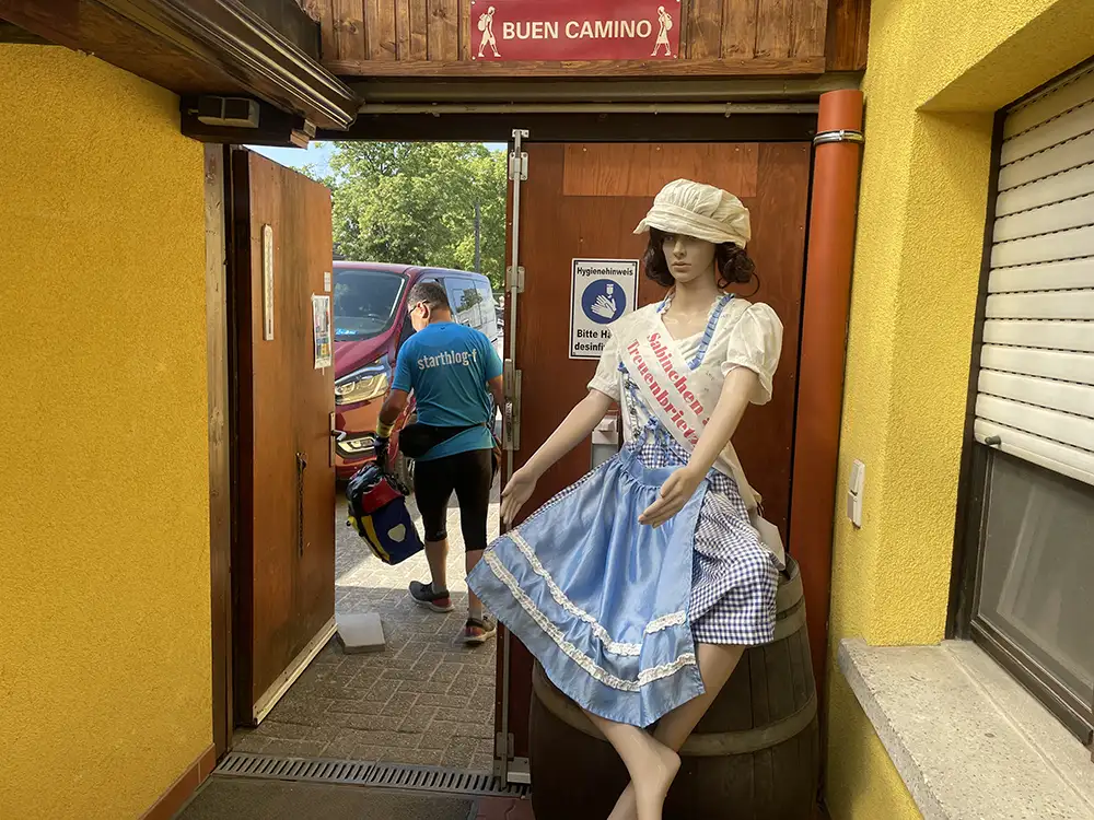 Frauenpuppe im Sabinchenkostüm sitzt auf einem Fass am Eingang