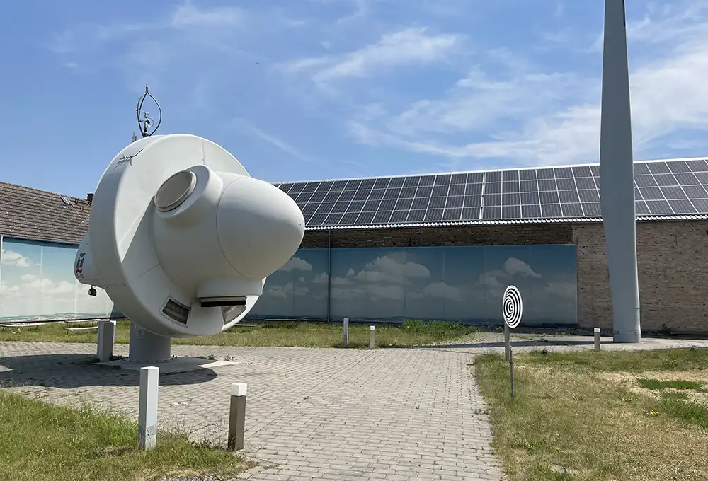 Ausstellungsgelände in Feldheim mit Windrad-Elementen im Hof und Solarpaneelen auf dem Dach