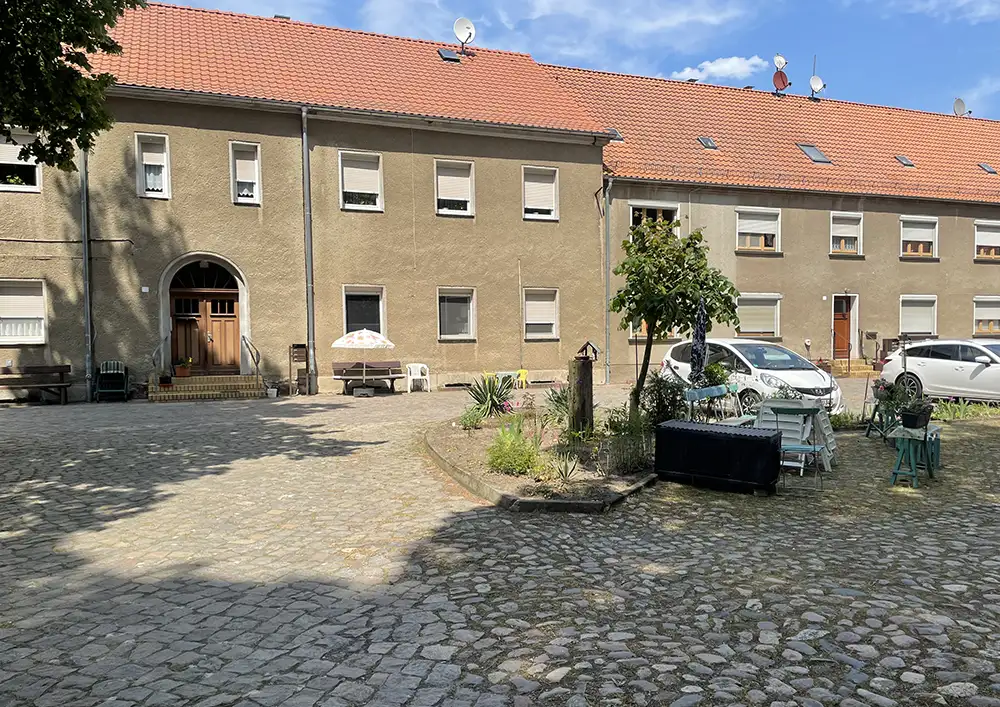 Häuserblock mit Innenhof,Tisch und Gartenstühlen und parkenden Autos