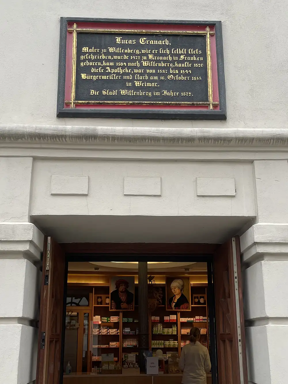Historisches Schild mit Informationen zu Lucas Cranach über dem Eingang der Cranach-Apotheke