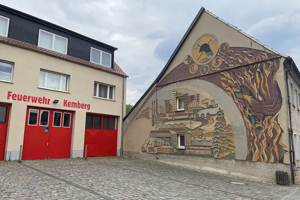 Gebäude Feuerwehr Kemberg, daneben ein großes Wandgemälde zum Thema Feuer und Ort