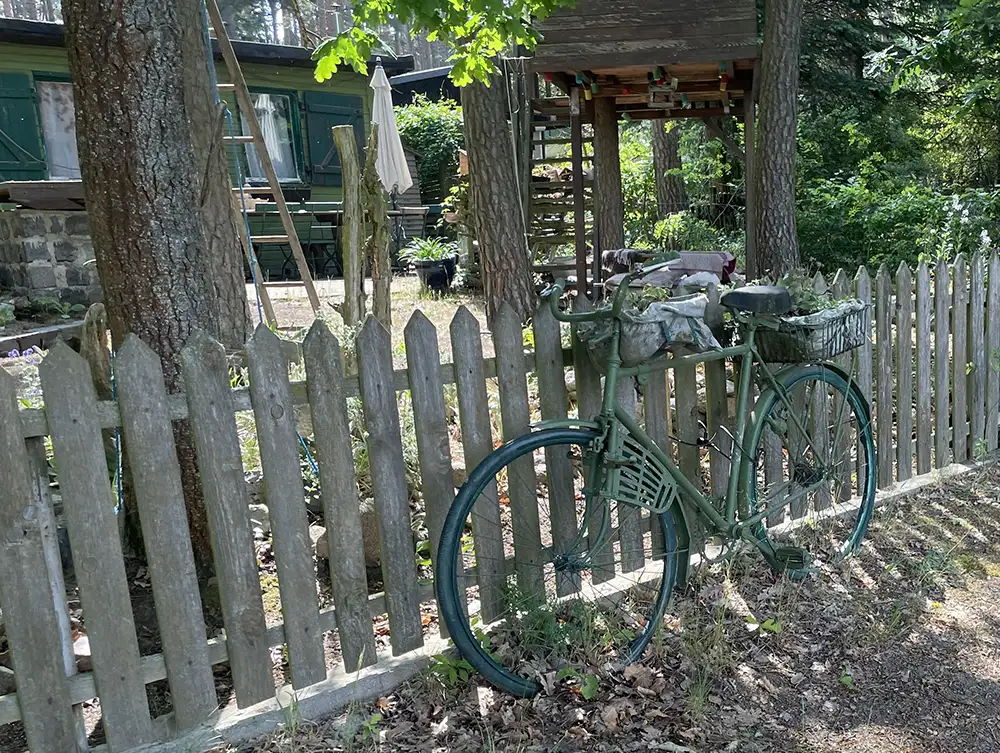 Altes grün bemaltes Fahrrad steht an einen Holzzaun gelehnt