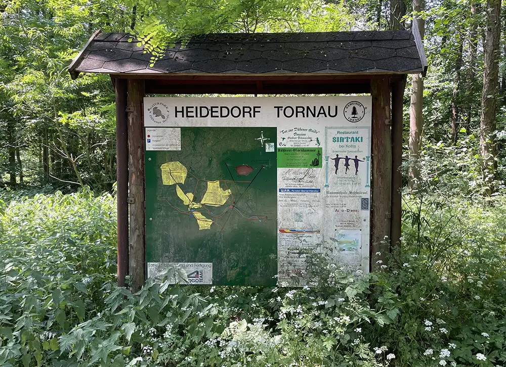 Überdachte Info-Tafel zum Heidedorf Torgau mit vergilbter Landkarte und Anzeigen von Handwerkern und Restaurants