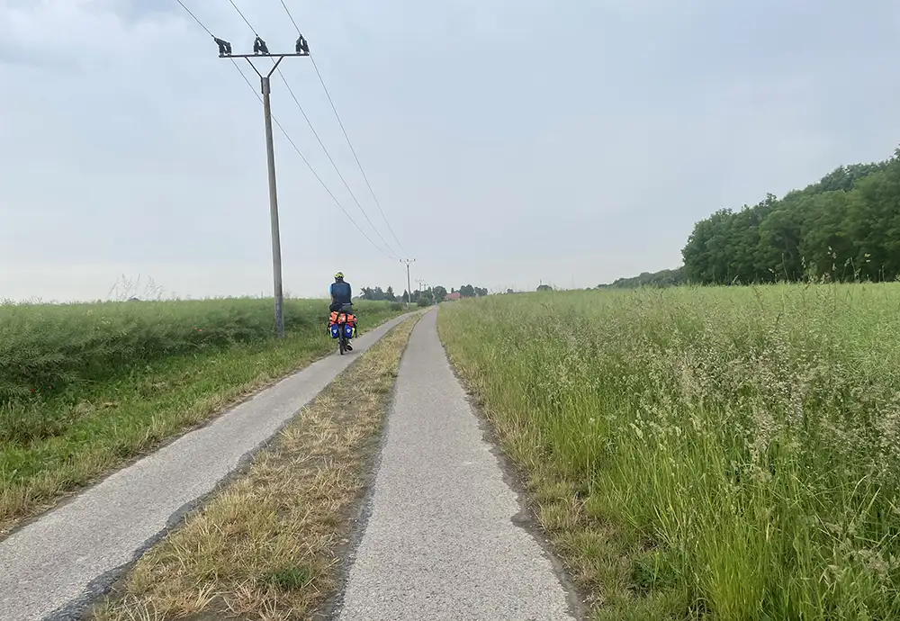 Fahrrad-Begleiter auf einem asphaltierten zweispurigen Weg, der sich bis zum Horizont zieht