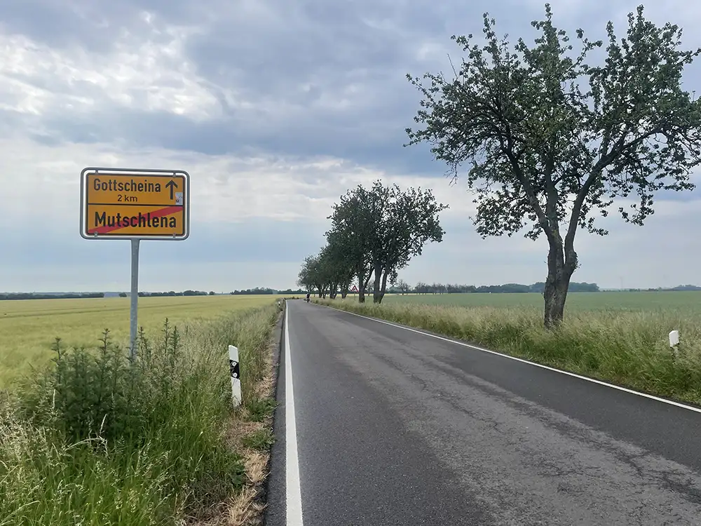 Landstraße mit Ortsausgangsschild Mutschlena, noch 2 km bis Gottscheina