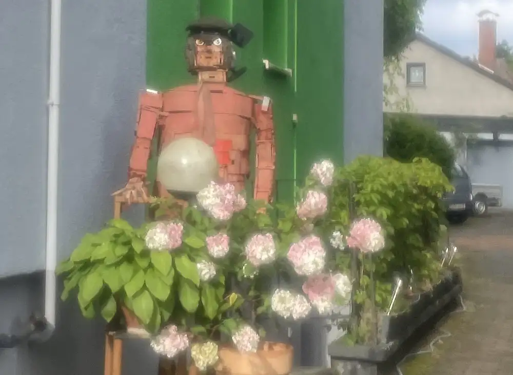 Selbstgebaute, lebensgroße Männerfigur vor einem Haus