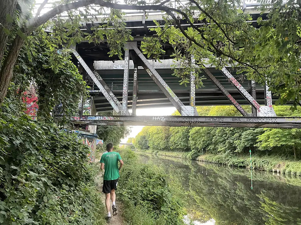 Läufer auf Pfad unter Stahl-Eisenbahnbrücke